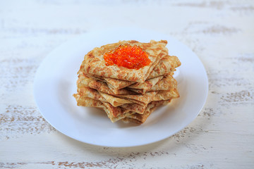 The Russian pancakes with a stuffing on a white plate on a light background. Maslenitsa.