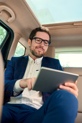Smiling businessman using a tablet during his morning commute