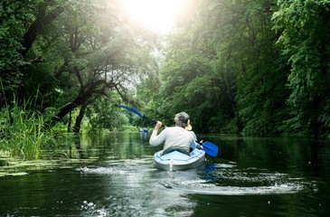 People canoeing on the river surrounded by dense green forest