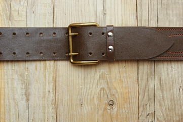 leather belt with a buckle on a wooden board