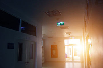 Fire escape on ceiling of corridor office building with morning sun light. Fire exit sign in the...
