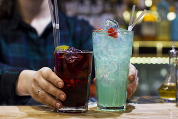 The girl bartender holding two drinks on the bar