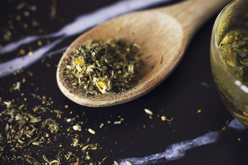 Herbal tea in a wooden spoon on a black marble background