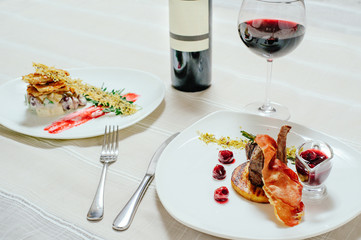 elegant appetizing veal with cherry sauce and turkey with Migdal. in white plates with greens, red wine and table setting