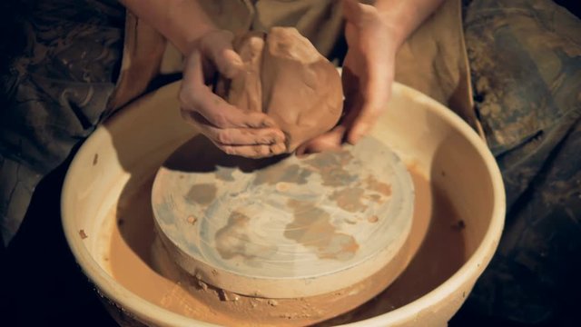 A potter brings together two lumps of clay. 