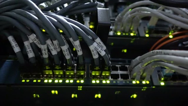 Working Ethernet switch in data center room, connecting computers together. Working Ethernet server. RJ45 jacks blinking LED lights. Close up. 