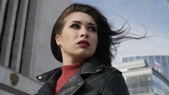 Brunette in leather jacket goes with suitcase