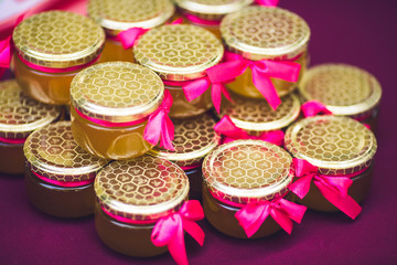 Beautiful cans with honey decorated with pink bows.
