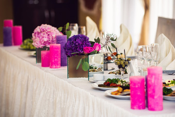 The decor of the wedding table: candles and a floral bouquet.