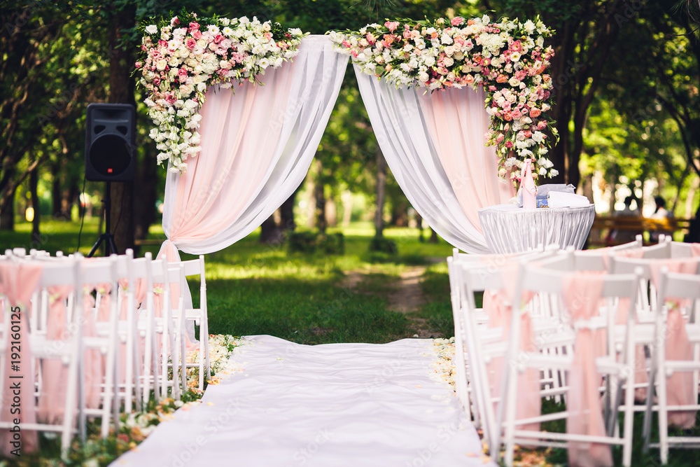 Wall mural Decor wedding ceremony in the summer in the park: an arch, chairs, flowers, path.