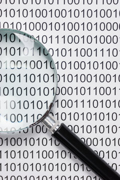 magnifying glass on a binary code