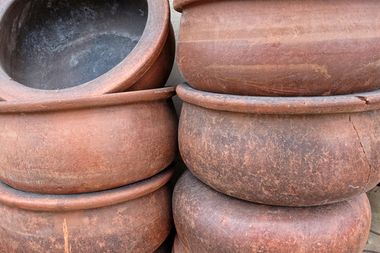 Handmade big clay casseroles stacked in front of the wall