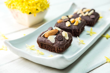Brownie cake with almond on top with yellow flower in the background