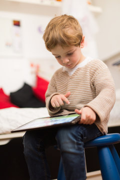 Blonde and cute boy playing with tablet