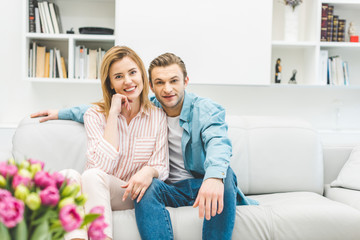 portrait of smiling couple resting on sofa at home