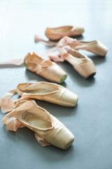 Ballet pointe shoes on the floor. Old used ballet slippers for girls on grey background. © DenisProduction.com