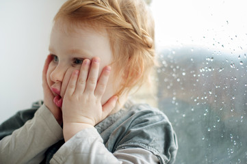 The girl squeezes her cheeks with her hands, she is surprised