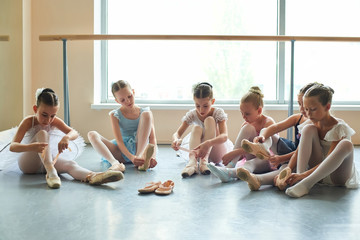 Fototapeta premium Group of young ballerinas preparing for performance. Six young ballet girls in ballet studio.