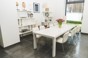 view of stylish empty dining room with bouquet of tulips on table