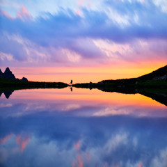 Couple silhouette by lake in mountains, colorful scenery full of love