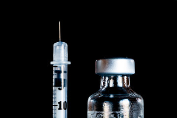 A syringe and vial on a black background