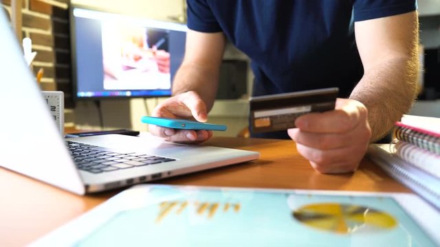 Hands holding credit card and using smartphone. Online shopping. Close view and very smooth dolly shot. 4K video with shallow depth of field focus on hands.