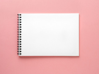 Blank notepad white page on pink desk, color background. Top view,  flat lay.