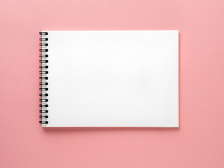 Blank notepad white page on pink desk, color background. Top view,  flat lay.