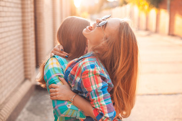 Two cheerful girls hugging outdoors