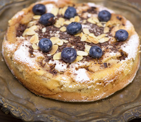 a round baked pie with apples and blueberries