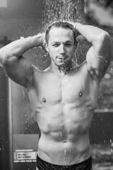 Young athletic muscular man taking an outdoor beach shower