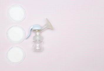 Manual breast pump with breast pads on the pink background