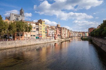 Obraz premium Colorful yellow and orange houses and bridge Pont de Sant Agusti reflected in water river Onyar, in Girona, Catalonia, Spain