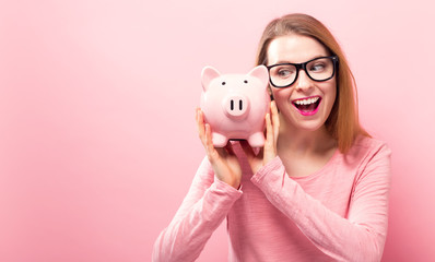 Young woman with a piggy bank on a solid background