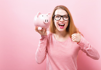 Young woman with a piggy bank on a solid background