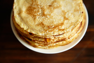Stack of pancakes with orange jam and honey on white cake stand on wooden table. Pancake breakfast concept