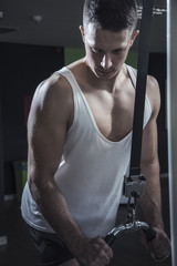 Obraz premium Young caucasian athletic man in the gym doing cable fly exercises