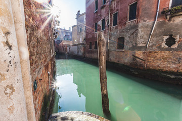 Typical Venetian canal illuminated by the rays of the sun, Venice, Italy
