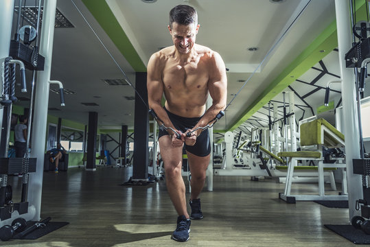 Young caucasian athletic man in the gym doing cable fly exercises