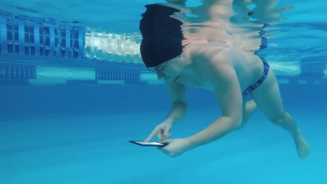 Man reads an electronic book underwater. This is a special waterproof electronic device. You can read the text and show signs directly underwater.