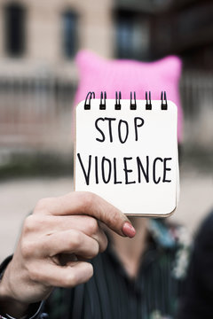 woman with a pink hat and the text stop violence