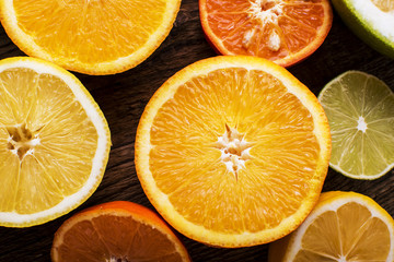 Fototapeta premium colorful citrus fruits, cut in half, on a dark old board