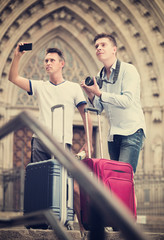 Male tourists with baggage at street taking photos