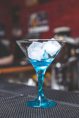 Glass for martini with ice cubes on a bar counter