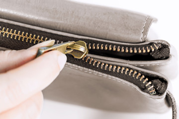 Golden brass zipper on a leather bag. The female is moving zipped open the bag.