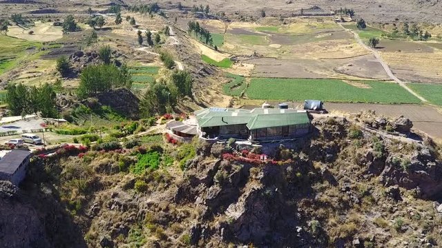 Aerial view circling around a beautiful house on the edge of a cliff over the Colca Canyon in Peru