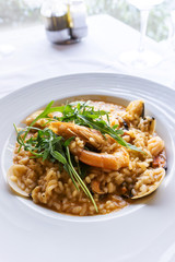 Tasty risotto with Shrimp, fresh herbs vegetables on a white plate