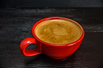 fresh aromatic coffee in a red mug on a black wooden background