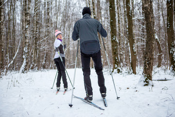 Image of sports woman and man skiing in winter forest