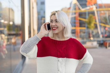 Portrait of cheerful young woman talking on smartphone outdoors.